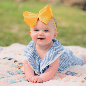 A baby laying down a mat outdoors in tummy time
